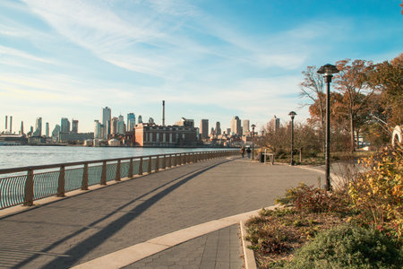 Sunrise on the East River Promenade in New York, USA. People strolling at dawn along the East River and on the other side the buildings of Brooklyn.の写真素材