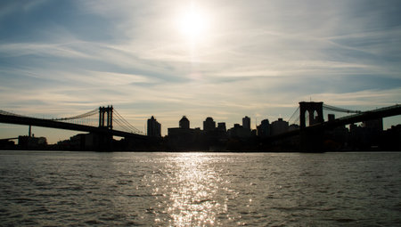 Sunrise from the East River Parkway, with the Manhattan and Brooklyn bridges on either side. Backlit...