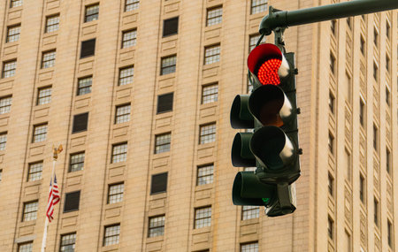 Red traffic light in New York City, USA. Traffic light and in the background the facade with windows of a residential building and the American flag. Traffic light in Foley Square.の写真素材