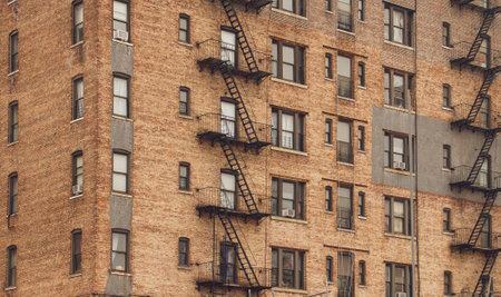 Cityscape of traditional brick architecture in Harlem, New York, USA. Metal fire escape as a main element of the facade of a residential building.の写真素材