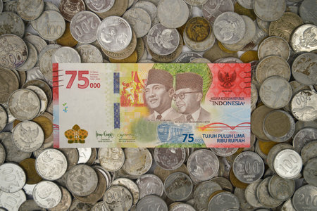 Yogyakarta, Indonesia - January 06, 2023: Special edition paper money for 75 years of Indonesian independence (rupiah) on a pile of coins of various shapes, year of manufacture and value.のeditorial素材