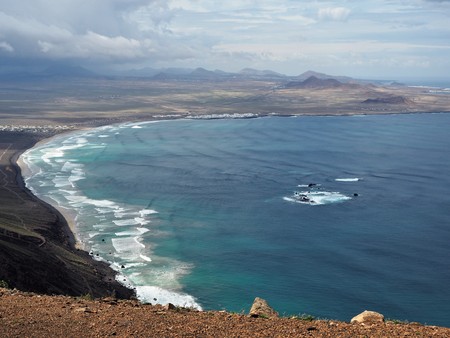 View over Playa de Famara with black volcanic cliffs, rocks and waves, Lanzaroteの写真素材