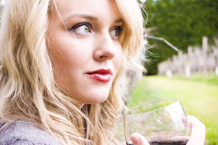Beautiful girl drinking wine in a vineyardの写真素材