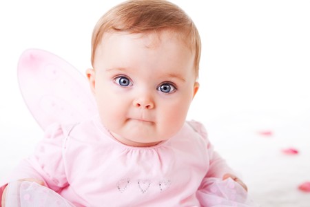 A cute baby girl wearing fairy wings stares wide-eyed at the camera.  Horizontal shot.の写真素材
