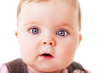 A cute baby girl looks in awe at the camera.  Horizontal shot.  Isolated on white.の写真素材