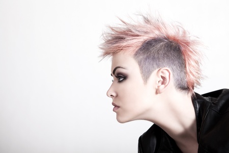 An attractive young female with a serious expression is wearing a punk hairstyle with pink hair. Horizontal shot.の写真素材