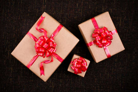 Christmas background - Gift box with red ribbon bow on dark brown background