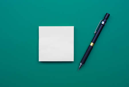 Note and Pencil on green background