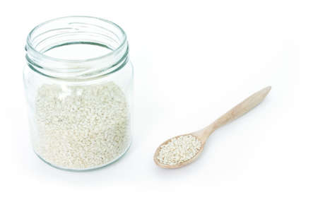 white sesame seed in jar and spoon on white backgroundの写真素材