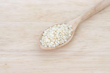 white sesame seeds in spoon on wood backgroud