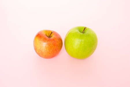 red apple and green apple on pink background