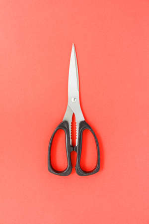 black scissors cutting on red backgroundの写真素材