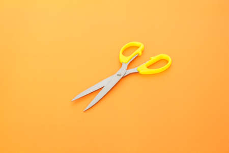 yellow scissors cutting on orange background