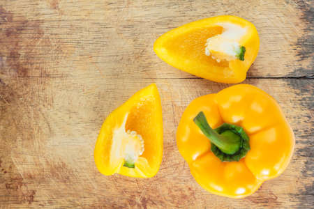 yellow bell pepper cut into pieces on wooden cutting board background, top view.の写真素材