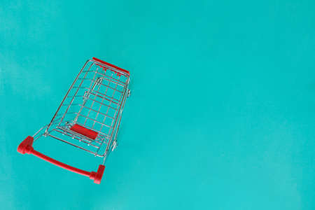 red shopping cart top view on green background.の写真素材
