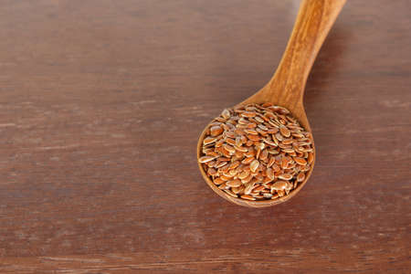 Brown flax seed in spoon on wooden background.の写真素材