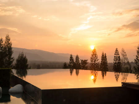 Open swimming pool with mountain background during sun set.の写真素材