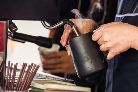 barista streaming milk for cappuccino coffeeの写真素材