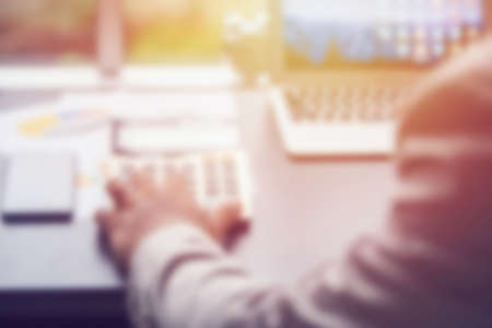 blurred hand pressing on calculator button and alarm clock, business conceptionの写真素材