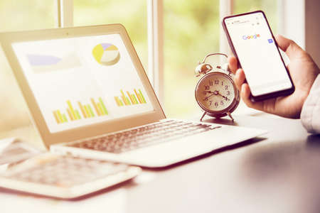 business man searching in smart phone and in formation in laptop screen, working against time