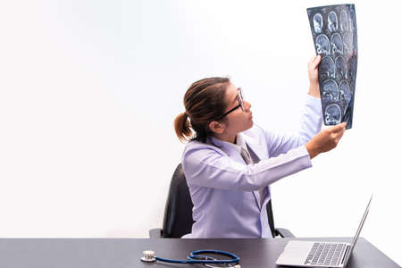 young female doctor holding MRI or CT scan picture, doctor in uniform sitting in working room and...