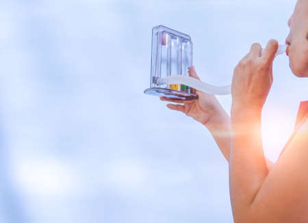 woman holding triflow and deep breathing to improve lung expansion, woman patient with chest rehabilitation by triflow deviceの写真素材