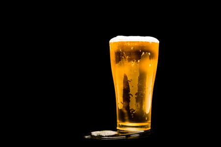 beer glass with white foam on dark background