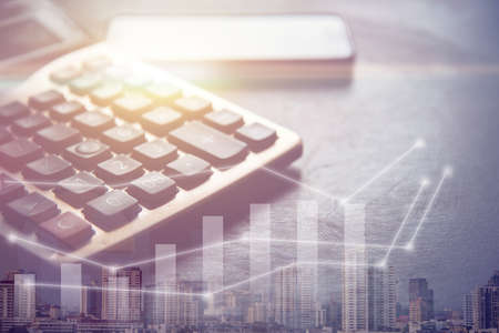 dark tone of calculator and smart phone, success graph and building in big city, business concept