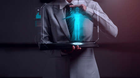 doctor holding holographic device with human anatomy graphic showingの写真素材