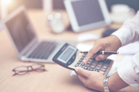 businessman with hand holding pen working on calculator to calculate business information dataの写真素材