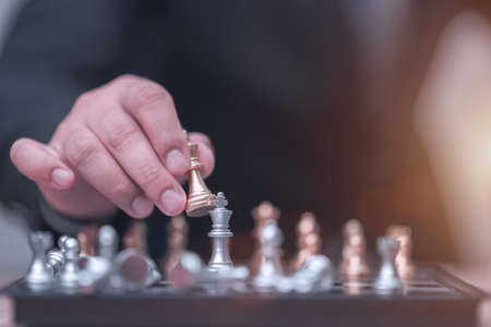 Business man holding golden king chess to finish gameの写真素材