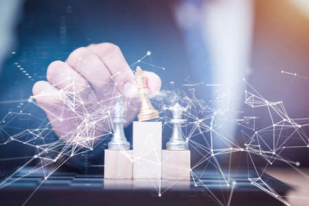 Business man holding golden king chess to winner position on wooden cube of the chess gameの写真素材