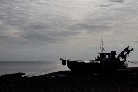 A silhouetted fishing boat on Aldeburgh Beach, Suffolkの写真素材