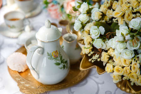 Flowers, ceramic teapot, marshmallows on a tray on the tableの写真素材