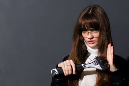 Girl in safety glasses with adjustable wrench on a dark backgroundの写真素材