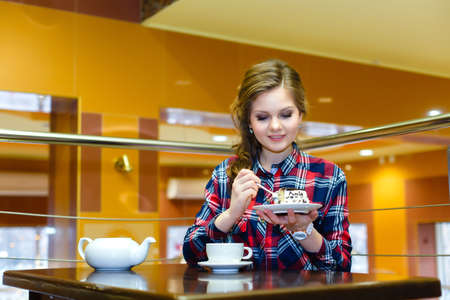Young beautiful woman eating cake in a cafeの写真素材
