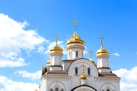 White Church domes with Golden crosses on the background of blue sky.