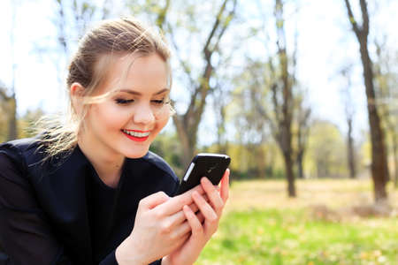 Woman with unkempt hair looking into smartphone smilingの写真素材