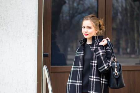 Young beautiful girl with a fashionable bag is standing on the streetの写真素材