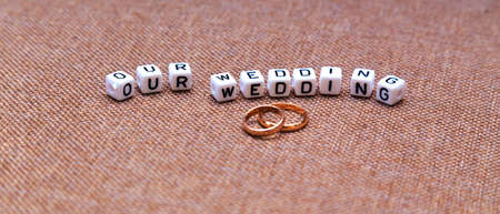 Inscription Our wedding and wedding rings on brown fabric texture. Focus on the inscription.の写真素材