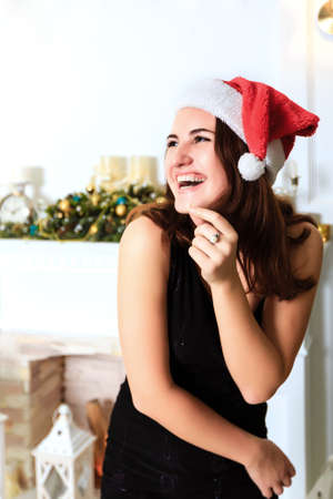 Laughing beautiful girl in the black dress and hat of Santa Clausの写真素材