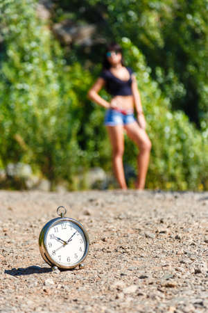 clock on the stone road and blurred girl at sunny day. it's time to travel
