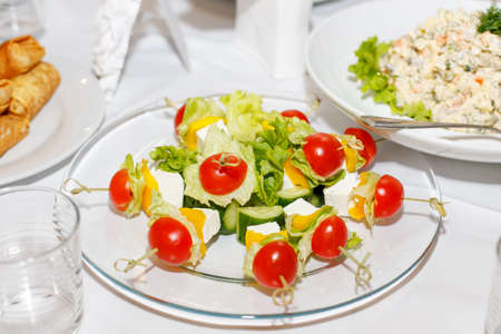 Canapes with tomatoes, cucumbers, cheese and greens on a banquet tableの写真素材