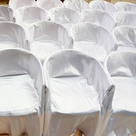 Chairs covered with white cloth on wedding ceremony in rowsの写真素材