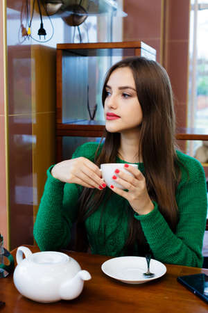 beautiful young woman drinking tea in cafeの写真素材