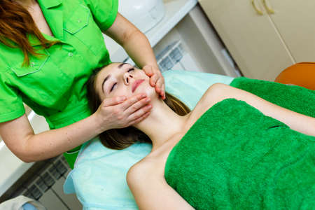 Young caucasian woman getting a face massage in spa salonの写真素材