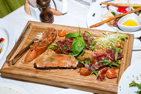 appetizers of seafood and meat on wooden plate in restaurantの写真素材
