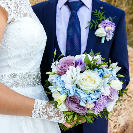 Bride and groom holding beautiful bouquet of roses outdoors. Square frame.の写真素材