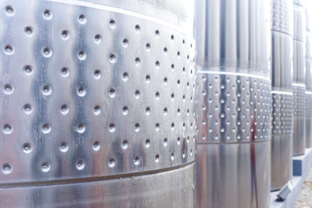 Modern technological industrial equipment of wine factory..Big stainless steel wine distilling tanks close up.の写真素材