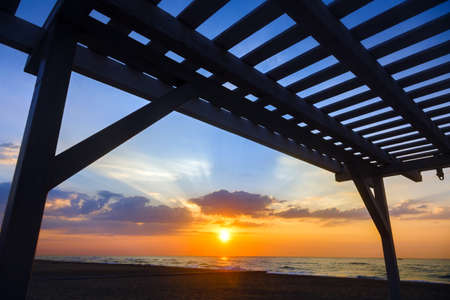 Silhouette of a wooden structure at sunset on a deserted beachの写真素材